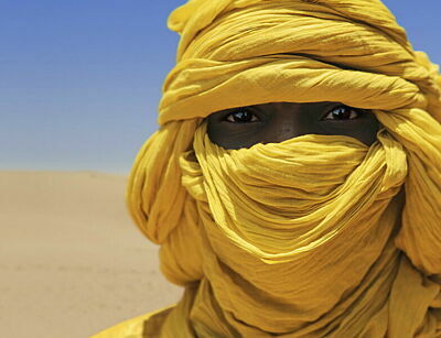 Tuareg mit leuchtend gelbem Tuch um den Kopf in der Wüste