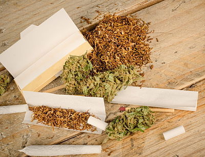 Cannabis, Tabak, Blättchen und fertig gedrehter Joint auf Holztisch