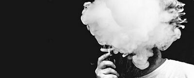 Kopf von Mann verschwindet hinter einer Wolke einer E-Zigarette