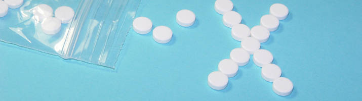 Auf einer hellblauen Tischplatte liegen Tabletten, ein Teil davon formt den Buchstaben X.