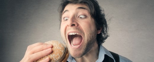 Mann reißt Mund auf, um in einen Hamburger zu beißen