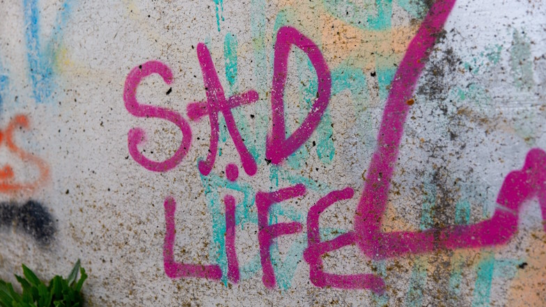Wand mit Graffiti-Schriftzug "Sad Life"