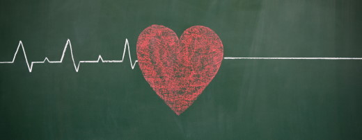 Auf grüner Tafel mit Kreide aufgemaltes EKG mit rotem Herz und Nulllinie