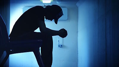 Silhouette einer sitzenden, vorübergebeugten Person