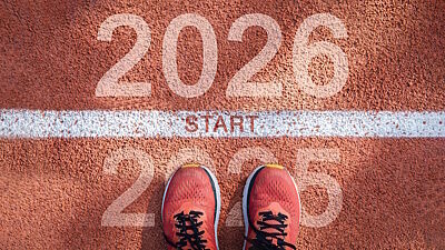 Eine Person steht vor der Startlinie einer Laufbahn, die das Jahr 2025 von dem Jahr 2026 trennt