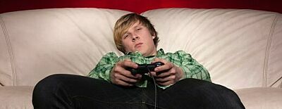 Junger männlicher Gamer hängt mit Controller auf Sofa ab