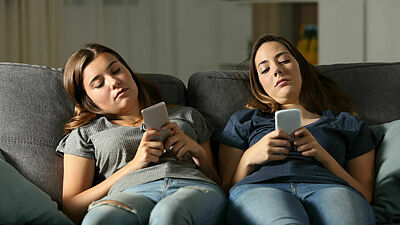Zwei Mädchen im Teenageralter schauen gelangweilt auf ihr Smartphone
