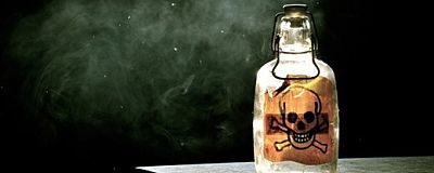 Flasche mit Totenkopfsymbol vor schwarzem Hintergrund