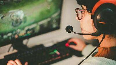 Weiblicher Teenager mit Headset und Tastatur vor Videospiel