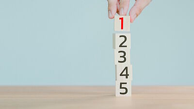 Hand bildet Turm aus Würfeln von 1 bis 5