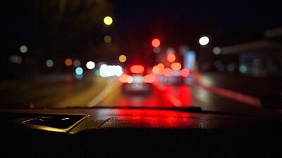 Blick aus einem Auto auf eine nächtliche Straße, die ins Unscharfe fällt