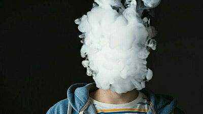 Kopf von einem Mann mit Kapuzenpulli verschwindet hinter einer Dampfwolke