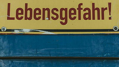 Schild mit Aufschrift "Lebensgefahr!" auf blauer Wand