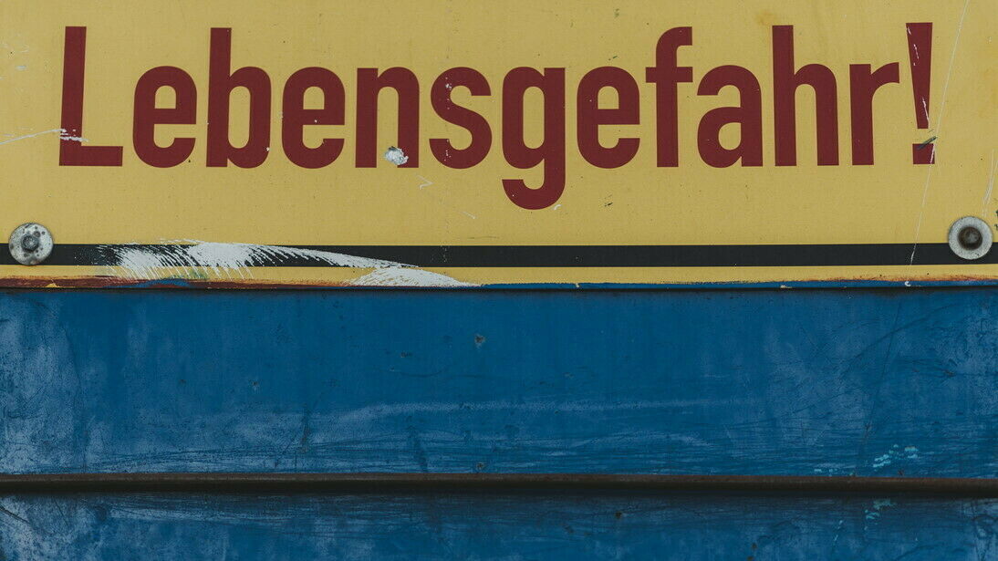 Schild mit Aufschrift "Lebensgefahr!" auf blauer Wand