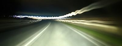 Langzeitbelichtung durch Frontscheibe Auto auf dunkle Straße mit Lichtern