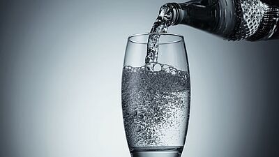 Sprudelwasser wird in ein Glas eingegossen