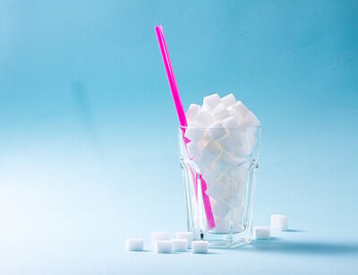 Ein Glas mit Zuckerwürfeln gefüllt vor hellblauem Hintergrund