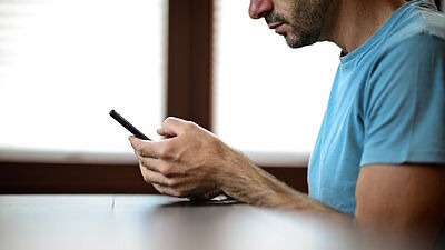 Mann mit Smartphone an einem Tisch