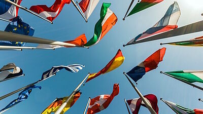 Flaggen europäischer Ländern von unten, dahinter blauer Himmel