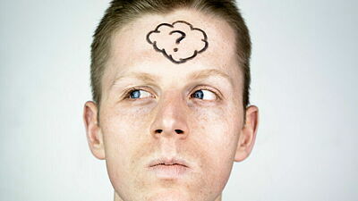 Junger Mann mit aufgemalter Wolke und Fragezeichen auf der Stirn