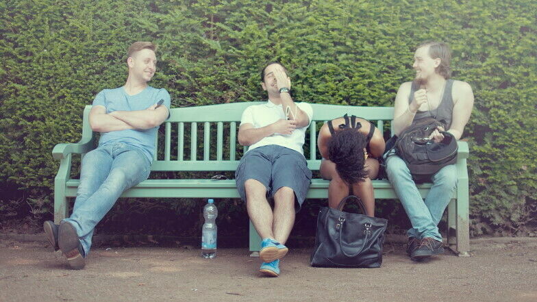 Junge Erwachsene sitzend lachend auf einer Parkbank