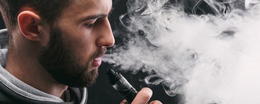 Mann mit E-Zigarette atmet Dampf aus