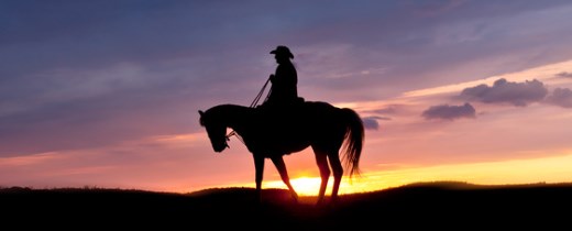 Einsamer Cowboy auf Pferd vor Sonnenuntergang