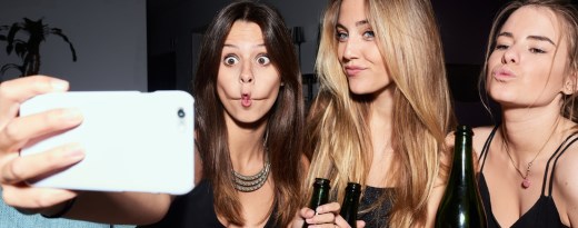 Drei junge Frauen machen Selfi mit Grimassen und Sektflasche in der Hand