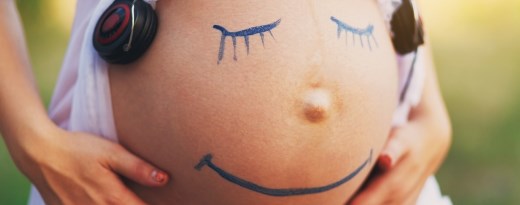Bauch einer Schwangeren mit aufgemaltem Gesicht