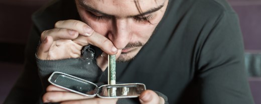 Mann konsumiert Kokain über einen zusammengerollten Geldschein