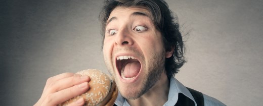 Mann reißt Mund auf, um in einen Hamburger zu beißen Mann reißt Mund auf, um in einen Hamburger zu beißen