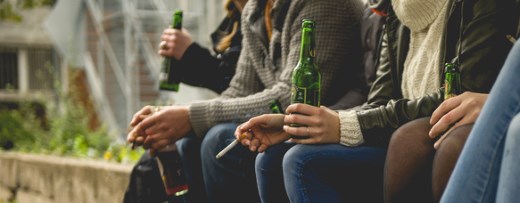 Junge Menschen mit Zigaretten und Bierflaschen in der Hand