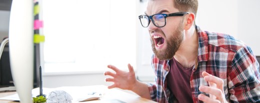 Mann schreit wütend auf seinen Computer ein