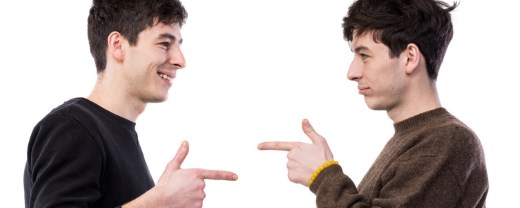 Lachende Zwillinge (junge Männer) zeigen gegenseitig mit dem Finger aufeinander
