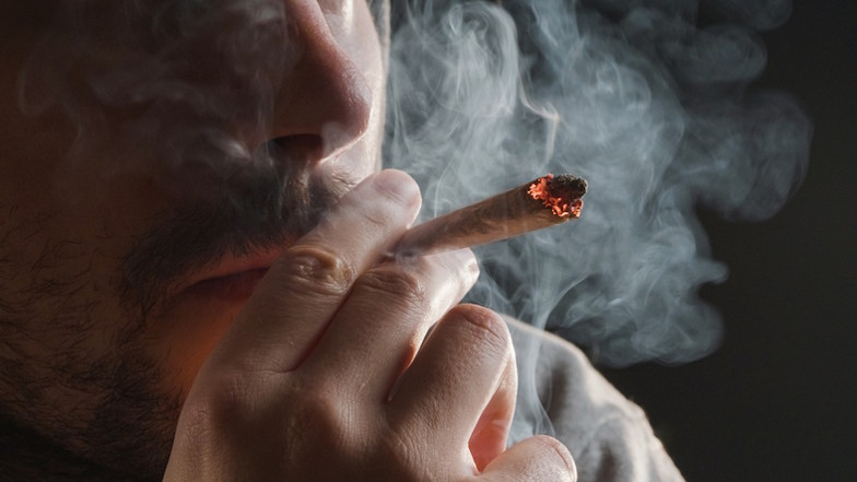 Nahaufnahme eines Mannes, der an einem Joint zieht.