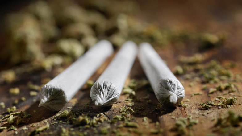 Drei gedrehte Joints, Marihuana-Krümmel drumherum