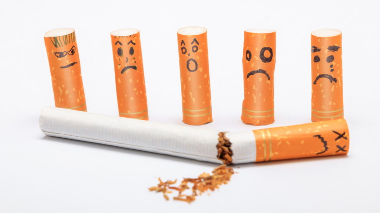 Zigarettenstummel mit aufgemalten Gesichtern stehen vor einer zerbrochenden Zigarette