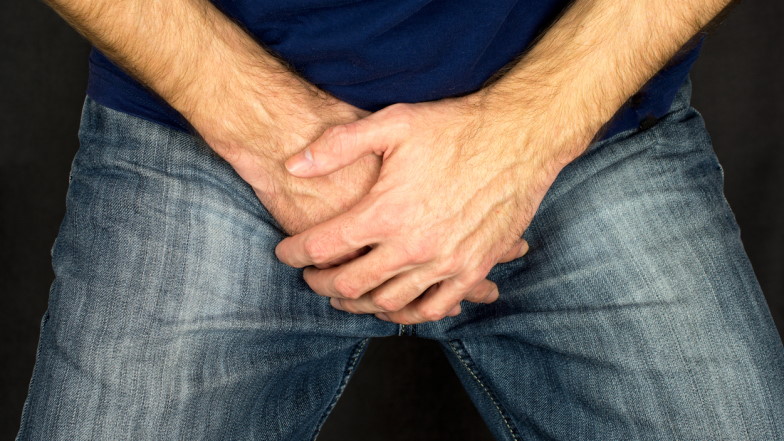 Mann in Jeans hält seine Hände schützend vor seinem Geschlecht