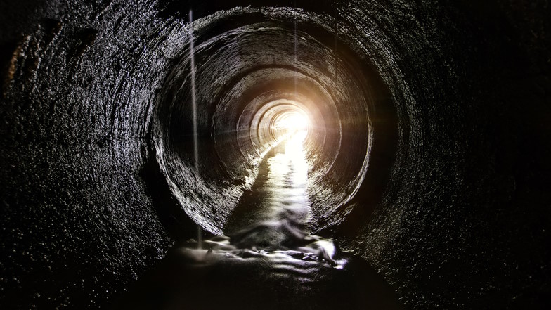 Abwasserkanal mit Licht am Endes des Tunnels