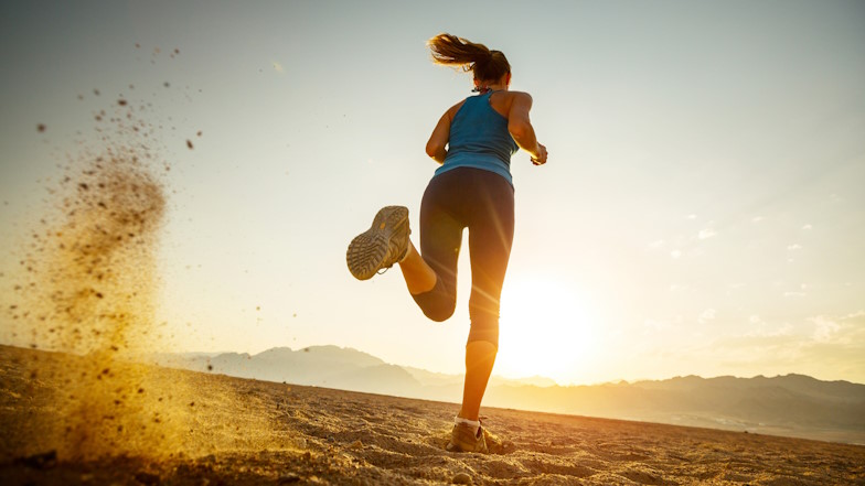 Gegenlichtaufnahme einer Joggerin am Strand 