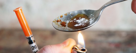 Heroin wird in einem Löffel über einem Feuerzeug für i.v.-Konsum vorbereitet