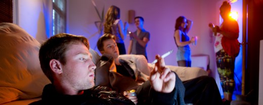 Partyszene - ein Jugendlich ist im Vordergrund mit einem Joint in der Hand