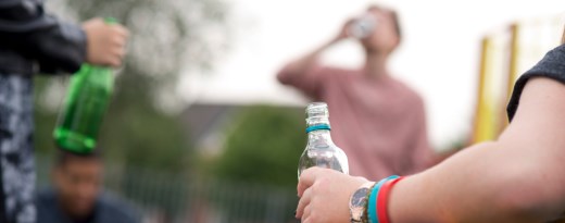 Vier Jugendliche trinken Alkohol auf einem Spielplatz