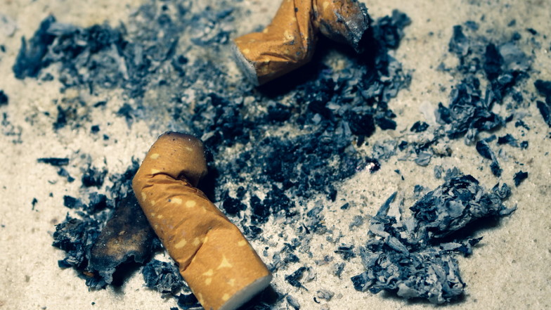 Zwei abgebrannte Zigarettenkippen im Sand