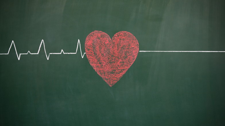 Mit Kreide auf Tafel gezeichnete EKG-Kurve, in der Mitte ein in rot gemaltes Herz