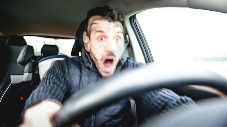 Autofahrer schaut erschrocken hinter dem Lenkrad