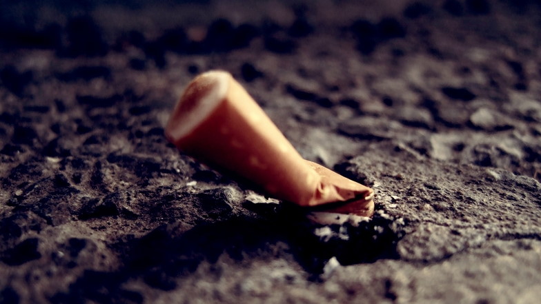 Nahaufnahmer einer eusgedrückten Zigarettenstummel auf Asphalt