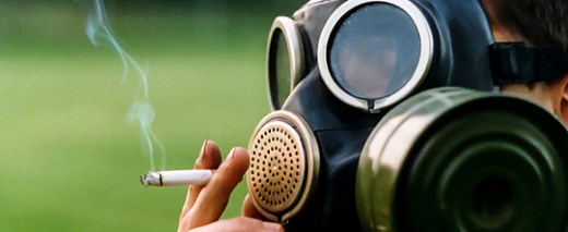 Person mit Gasmaske "raucht" eine Zigarette