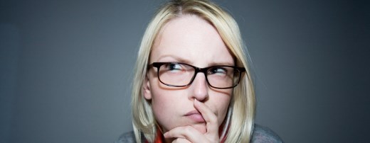 Frau mit Brille stützt sich auf Hand und schaut denkend nach rechts oben