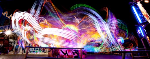 Leuchtende Farbverläufe durch Langzeitaufnahme von einem Jahrmarktskarussel in der Nacht